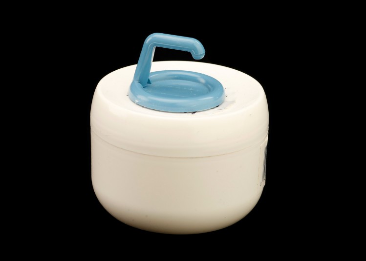 A blue adhesive plastic hook is affixed to the top of a cold cream jar. The hook allows Cindy to grasp and turn.