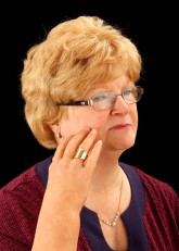 Headshot of Cindy wearing right cosmetic hand and scratching her face with the nails.