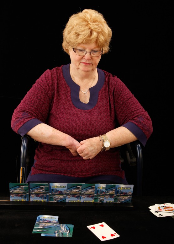 Cindy sitting at a table with card holder in front of her, and cards played in front of her.
