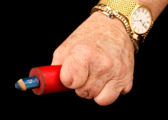 Cindy's hand holds a blue eyeliner pencil encased in red rubber tubing.