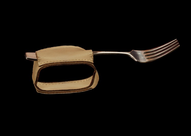 Studio shot of a silver fork on a light-brown leather fork cuff. The fork reaches from left to right across the screen.