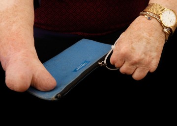 Cindy's right hand steadies a zippered purse, while her left hand grabs the cable tie and zips it shut.