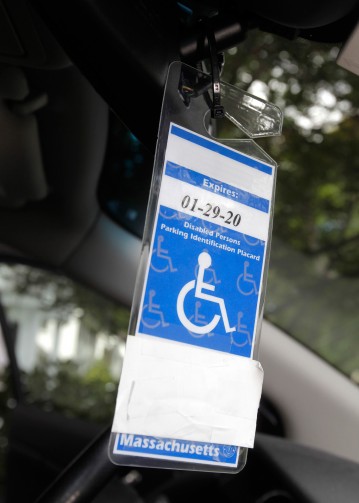 A black plastic cable tie affixes the accessible parking permit to Cindy's car, for easy on-off movements.