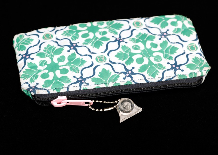A flowered purse with a zipper opening. Cindy has attached a metal linked key chain with a clear plastic fob to the pink zipper pull.